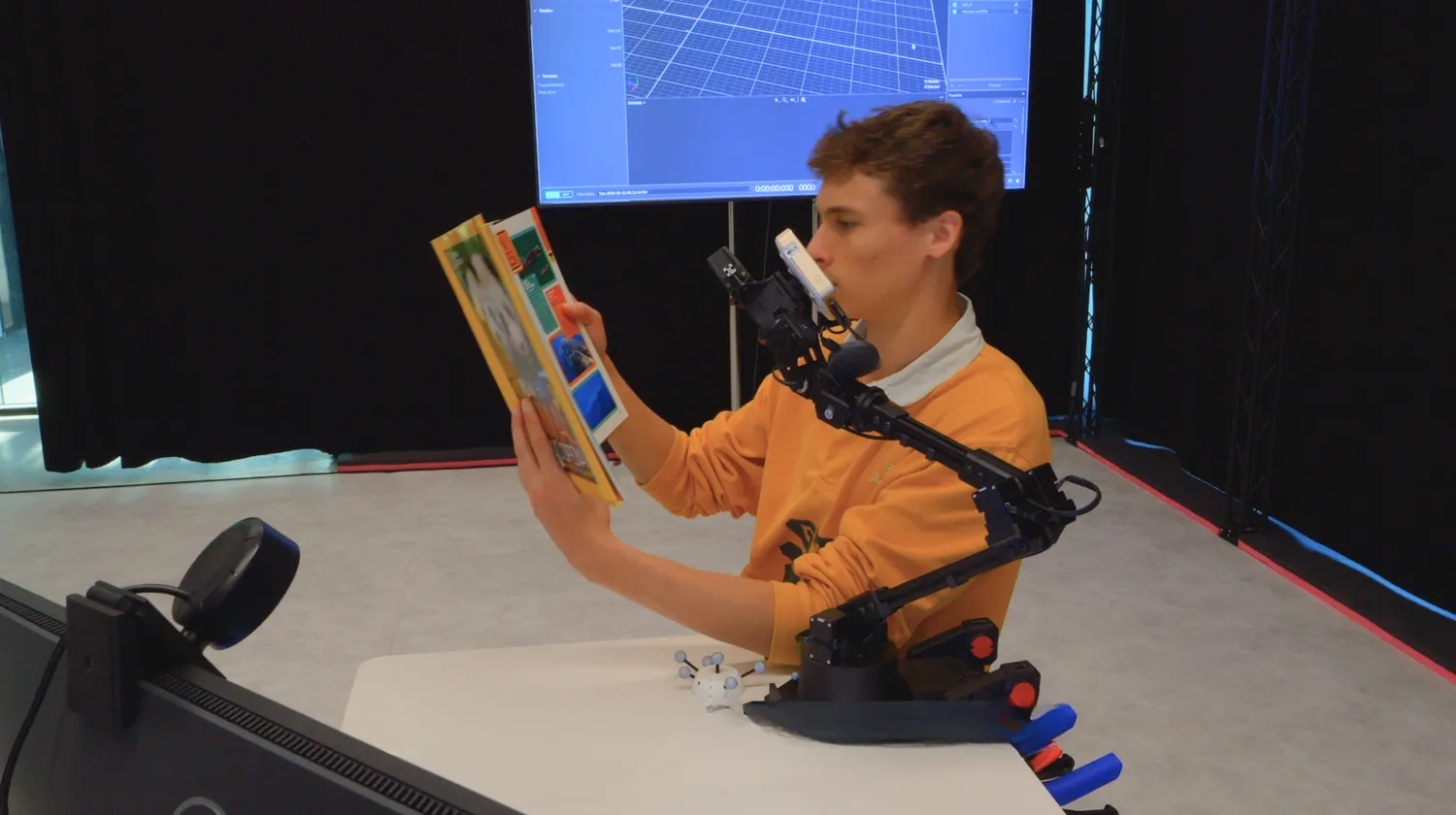 A person working at a desk while the AIfred robot arm holds a projector over their work.